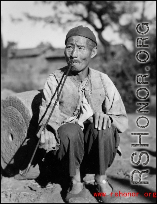 An elderly villager with a long pipe in China, probably in Yunnan province. During WWII.
