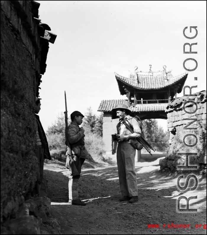 A photographer walking the paths of a village in Yunnan province stops to engage a Chinese soldier.