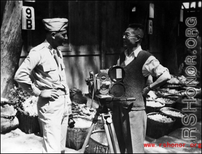 An American photographer (left) talks to a civilian, probably also a photographer (right), at a market in a village in Yunnan province.