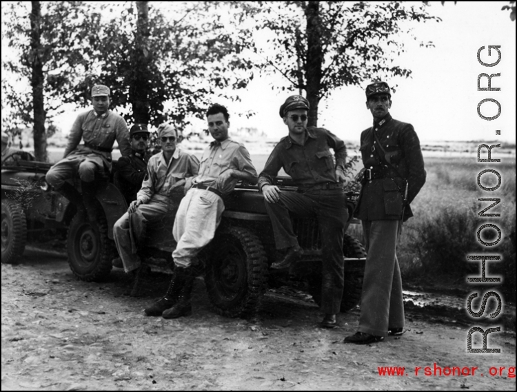 Americans and Chinese socialize while lounging on jeeps, in the CBI.