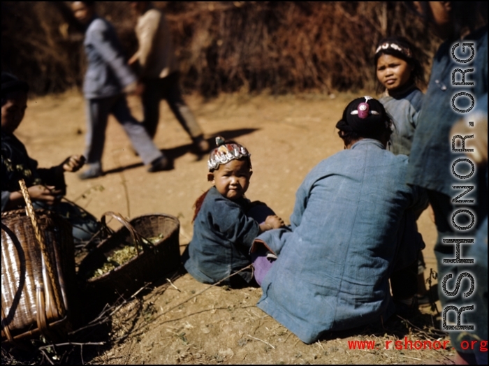 An infant with a colorful hat sitting.  At a rural village near the American base at Yangkai, Yunnan province, in the CBI.