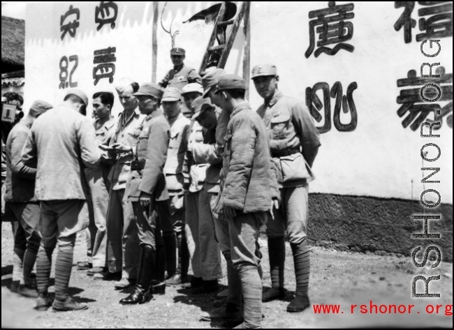 Americans and Chinese in the CBI in front of wall covered in propaganda. During WWII.