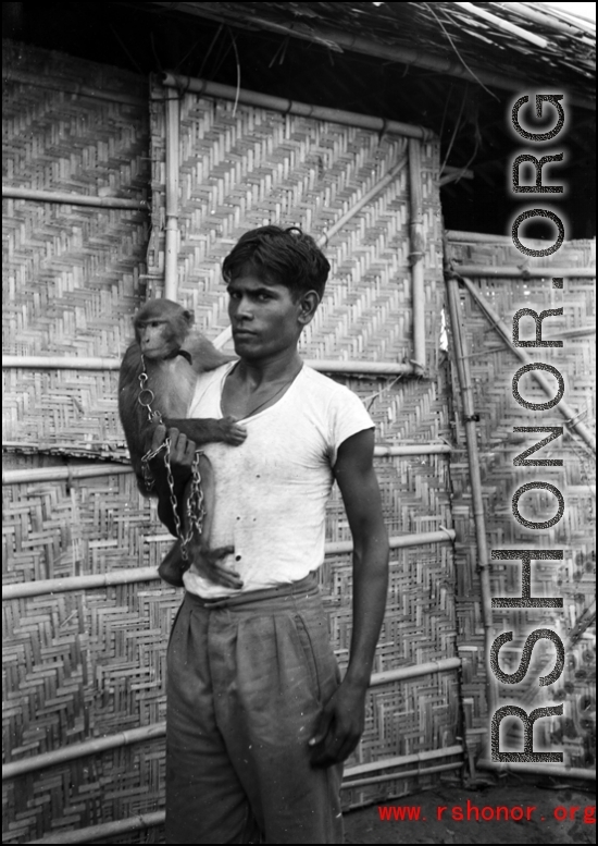 A man poses with a chained monkey in India during WWII.    From the collection of David Firman, 61st Air Service Group.