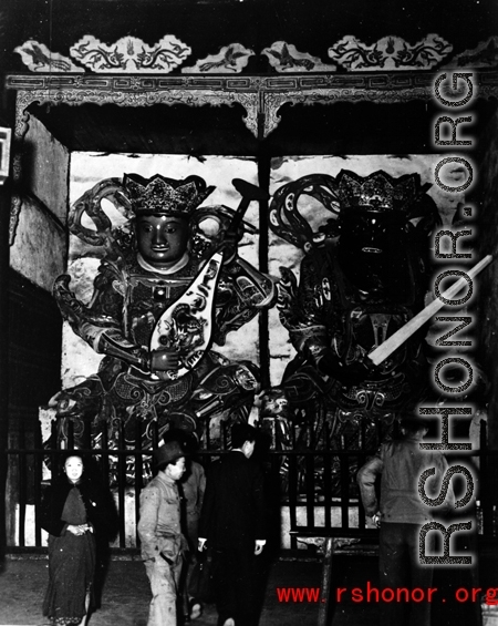 People look at the protective deities at the entrance to a Buddhist temple in China during WWII.
