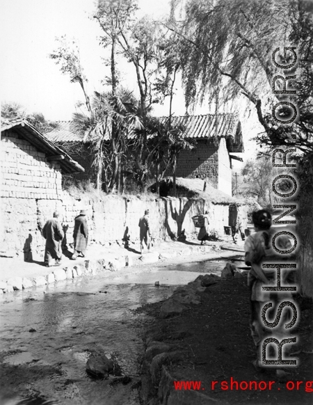 Local people near Yangkai, Yunnan province, China, walk a village pathway. During WWII.