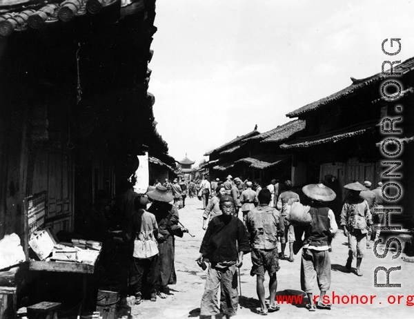 Local people in Yunnan province, China: A town street with drum tower (or bell tower) at the center. During WWII.