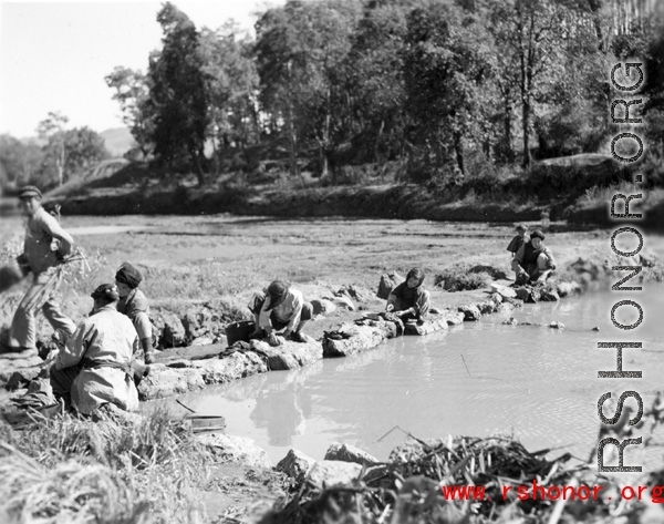Local people in Yunnan province, China: Women washing clothing in village. During WWII.
