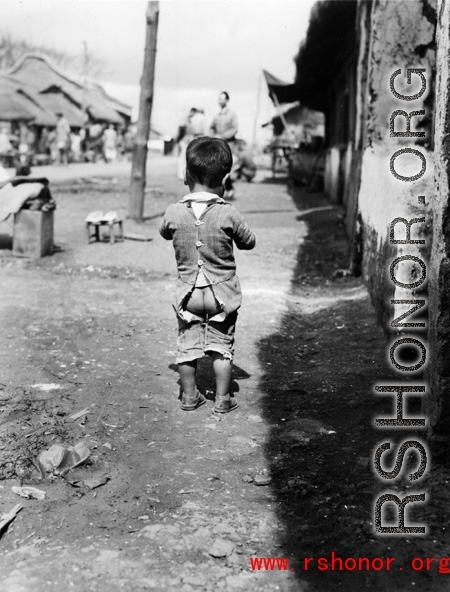 Local people in China: A young child with split pants in a street in China, during WWII.