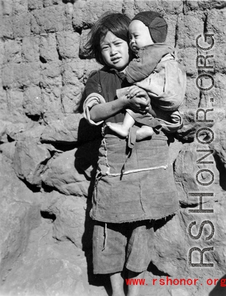 Local kids in Yunnan province, China, during WWII: A girl holds an infant.