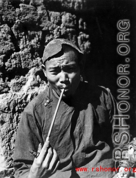 Local people in China: Village man smokes modest pipe, during WWII.