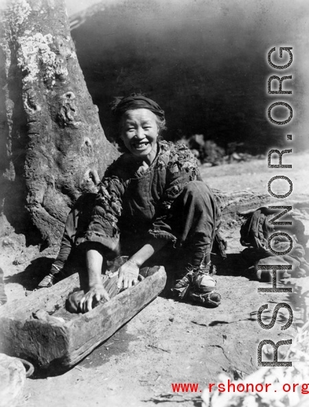 Woman washes clothing in wood trough. In Yunnan, China, during WWII.