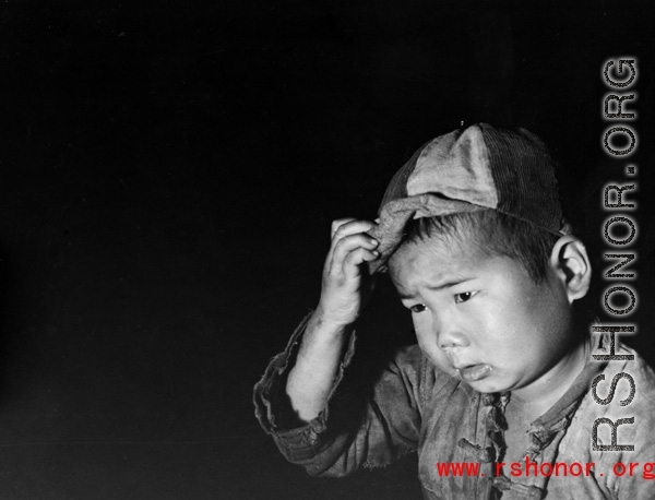 Local people in China during WWII: A Chinese child wearing a cap.