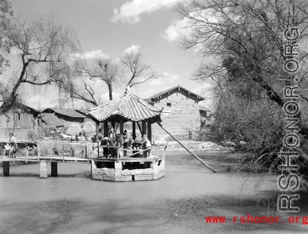 Local people and American visitor in a pavilion over a small pond near Yangkai,  Yunnan province, China. During WWII.