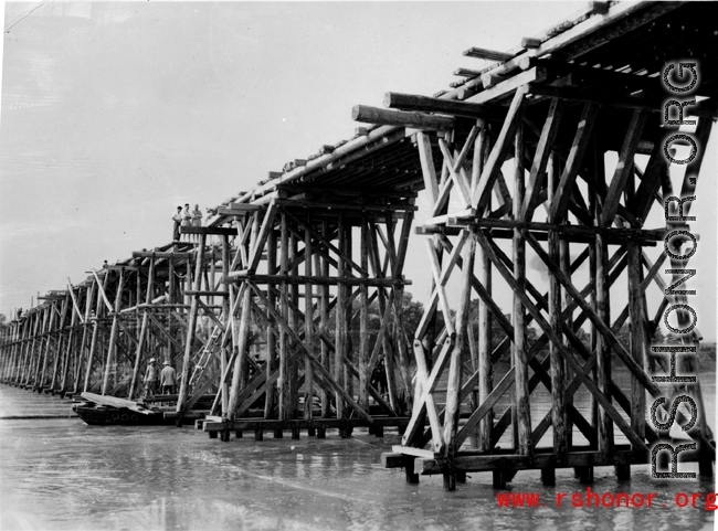 Allies building a wooden trestle bridge across a river in the CBI during WWII.