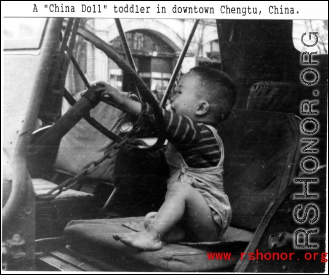 A Chinese toddler playing on a the driver's seat of a jeep in downtown Chengdu, China, during WWII.