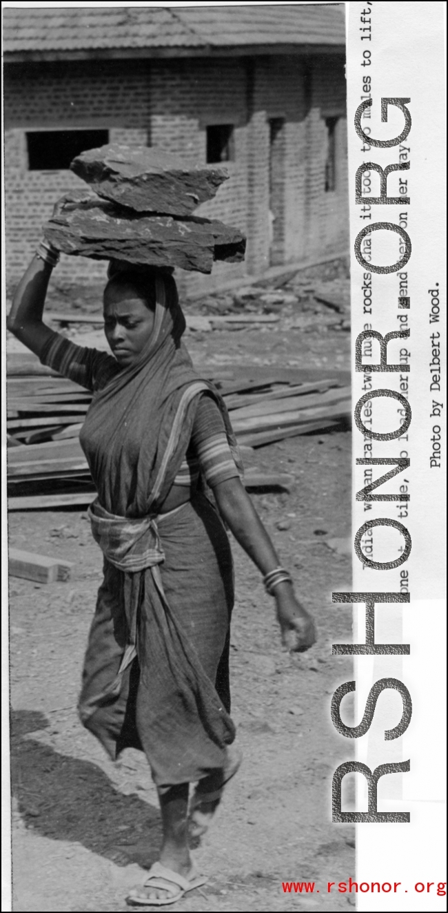 An Indian woman carries two huge rocks on her head at a construction site. During WWII.  Photo from Delbert Wood.