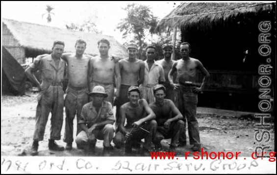 Men of the 1791st Ordnance Company, 52nd Air Services Group, pose for a photo in front of huts, during WWII.