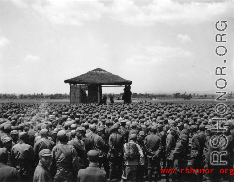Chinese soldiers standing around a stage during a ceremony in southern China, probably Yunnan province, or possibly in Burma.
