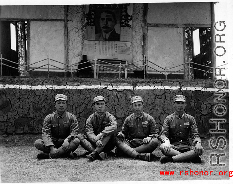 Chinese soldiers sit cross-legged in front of stage during rally in southern China, probably Yunnan province, or possibly in Burma.