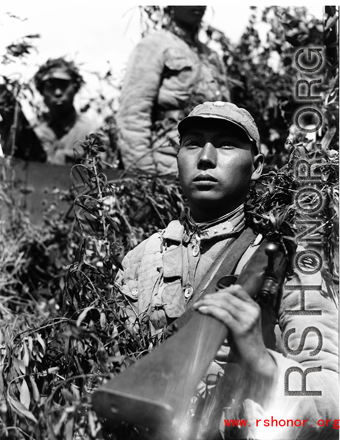 Chinese soldiers with equipment ready and covered in camouflage during exercises in southern China, in Yunnan province, including this Nationalist soldier with rifle over shoulder.