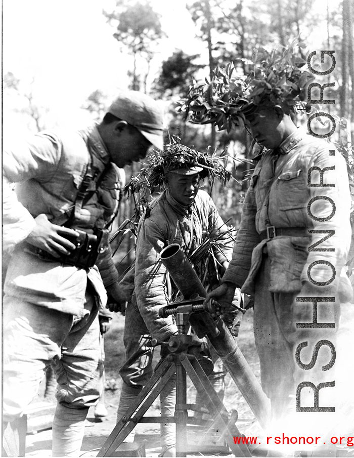 Chinese soldiers with mortar ready, and covered in camouflage during exercises in southern China, in Yunnan province.  Despite the appearance of being on their way to battle, these men are more likely in fact prepared for a demonstration or honor parade. 