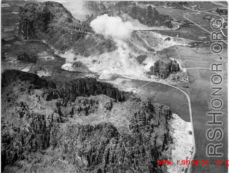 A fortified karst rock outcrop, certainly with a Japanese troops dug in or nearby, is bombed in southern China or Indochina during WWII. Notice the bomb crater to the left--the site has been bombed before.