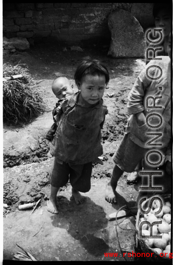 A child bearing a baby on her (most likely) back, during WWII, in Yunnan, China.