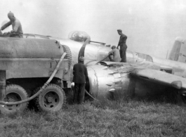 Member of 12th Air Service Group recovering fuel from crashed Nationalist-marked B-25: "Gasoline was a precious commodity in China. All the gas we received had to be flown over the Hump from India into China. This picture shows some members of the 396th pumping gasoline out of the wing tanks of a crashed B-25. With the supply situation of everything having to flown over the Hump nothing was wasted and all serviceable parts were salvaged." Caption courtesy of Elmer Bukey.