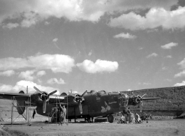 Sichuan (China), B-24 'Doodlebug' being prepared for a mission: "Set in the safety of a reverted hardstand, this B-24 heavy bomber was being readied for a mission. The lady riding a bomb was the trademark of this aircraft named 'Doodlebug' by its crew members. The row of bombs indicate missions carried out. The small Japanese flags represent enemy aircraft shot down. This is an early model plane. Later model B-24's were equipped with a nose gun turret. The turrets provided better target coverage and firepow