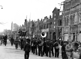 A funeral procession in China during WWII, with musicians and mourners. The large placard being carried says 福寿无疆, something like Limitless Good Life.
