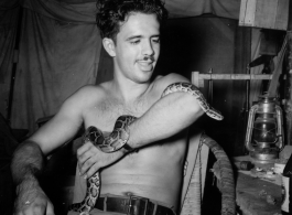 Engineer of the 797th Engineer Forestry Company poses with snake in tent in Burma.  During WWII.