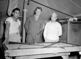 Engineers of the 797th Engineer Forestry Company pose while playing at a miniature pool table in their tent in Burma.  During WWII.