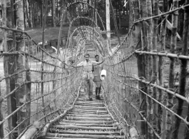 Men, likely Indian soldiers, on a vine and branch bridge in Burma or India.  Near the 797th Engineer Forestry Company.  During WWII.