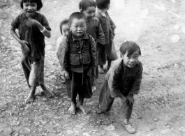 Chinese children, including one who is carrying a baby on his back. During WWII, in SW China.