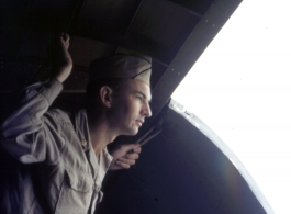 A flyer gazes out of the open cargo door of a cargo aircraft (a C-47 or C-46) during WWII.