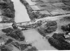 Bomb railroad bridge in French Indochina (Vietnam), during WWII. Note train engine on its side in water, and rebuilt temporary bridge nearby.  22nd Bombardment Squadron, 2nd Group.