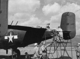 "With Chinese Military Guard Standing Close By, Ground Crew Of The 14Th Air Force Work On A North American B-25, Preparing It For Another Raid On Enemy Installations."  A ground crew of the 341st Bombardment Group does maintenance to the tail gunner position on a B-25, which appears to have already had a field modification, possibly in Chakulia.