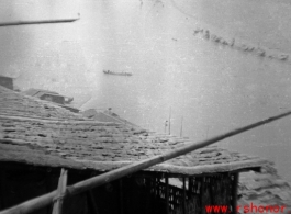 Houses clustered on the Yellow River during WWII, possibly in or near Lanzhou, and a boat in the river.