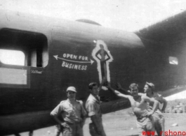 Men pose next to artwork of the tail of B-24 "Open For Business" of the 308th Bombardment Group.
