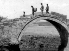 Chinese pedestrians cross arched stone bridge in SW China during WWII.