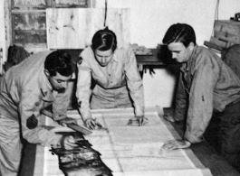 Men from the 21st Photographic Reconnaissance Squadron examine some photographs. In China, during WWII.