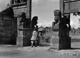 Two women walk through a ceremonial gate in Yunnan province during WWII.