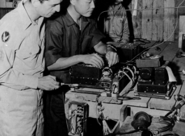 CHINESE AIRMEN GET AMERICAN TRAINING AND EQUIPMENT, 29 January 1944.  Communications is an important phase in the training of the Chinese American Composite Wing (CACW) .  Here, on January 29, 1944, Lt. Kwang Chao-Li checks a defective radio receiver at a test bench in the hanger.  Sgt. Anthony Puflia, Paterson, New Jersey, left, stands by to offer assistance while Sgt. W. L. Whisenant, Chostow, Oklahoma, right, continues with his own duties.  During WWII in China.  Images courtesy of Tony Strotman.