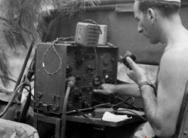 A GI operates a portable radio from the back of a vehicle in the CBI during WWII.