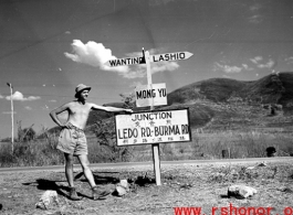 GI leans against sign at junction of Ledo Road and the Burma Road, during WWII.