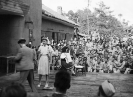 Celebrities (including Ann Sheridan, Ben Blue, and and Ruth Dennis playing an instrument in this shot) perform on an outdoor stage set up at the "Last Resort" at Yangkai, Yunnan province, during WWII. Notice both Americans and Chinese in the audience for this USO event.