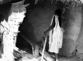 A woman uses a "dhenki" foot lever for dehusking grain. India.  Scenes in India witnessed by American GIs during WWII. For many Americans of that era, with their limited experience traveling, the everyday sights and sounds overseas were new, intriguing, and photo worthy.