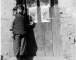 Local girl Shu Mei Chow stand before door decorated with door gods near the time of Chinese New Year in the village of Siang Shi Tsah, during WWII. Some of these were put out by the OWI in color.