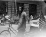 Pedal-taxi driver with American flag. Probably after the end of war, in a large city like Shanghai.