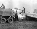 Member of 12th Air Service Group recovering fuel from crashed Nationalist-marked B-25: "Gasoline was a precious commodity in China. All the gas we received had to be flown over the Hump from India into China. This picture shows some members of the 396th pumping gasoline out of the wing tanks of a crashed B-25. With the supply situation of everything having to flown over the Hump nothing was wasted and all serviceable parts were salvaged." Caption courtesy of Elmer Bukey.